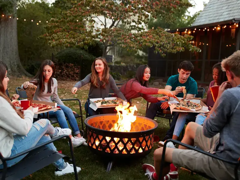 People gathered around a fire pit at a bug-free backyard party.