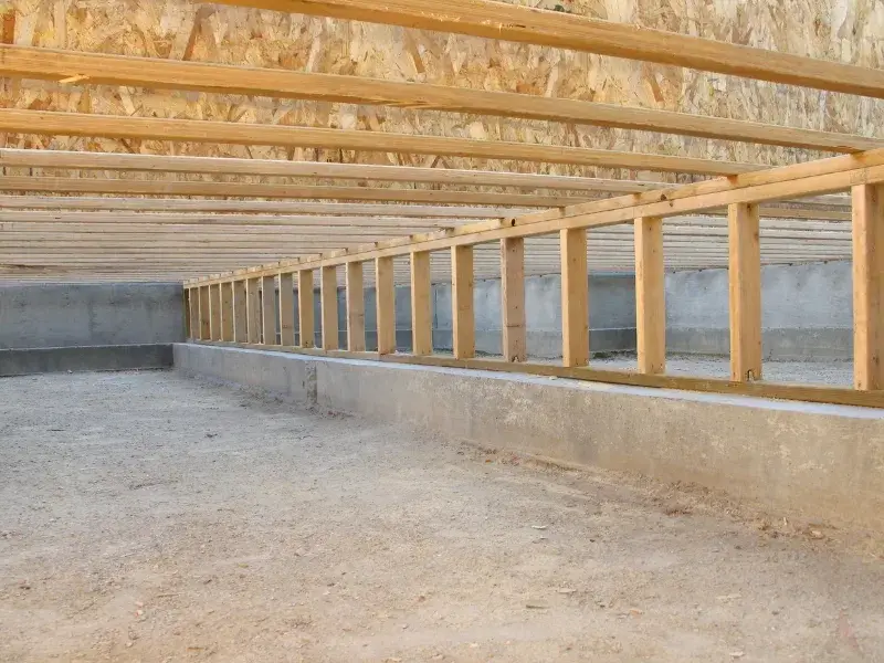 The framing of the underside of a house, highlighting the need for crawl space encapsulation in West Jefferson, NC.