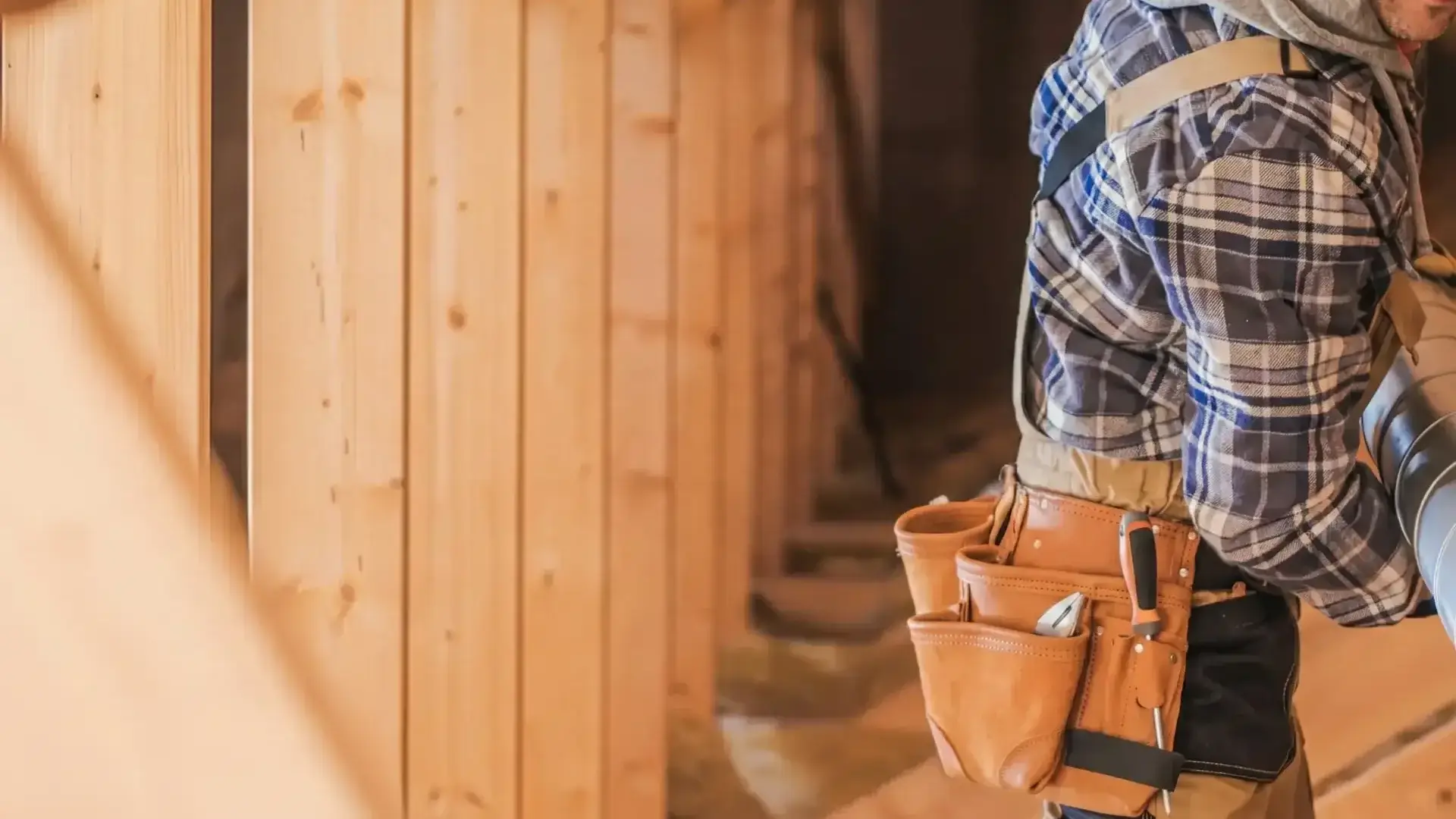 a man with a tool belt around plywood boards.